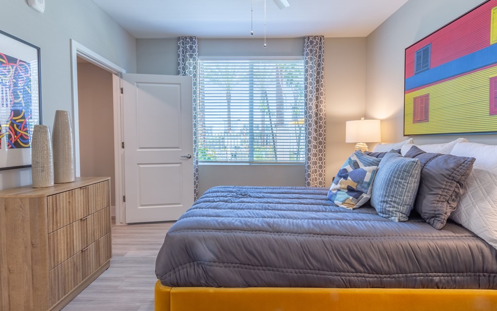 A bedroom with a bed, a dresser, and a painting on the wall.