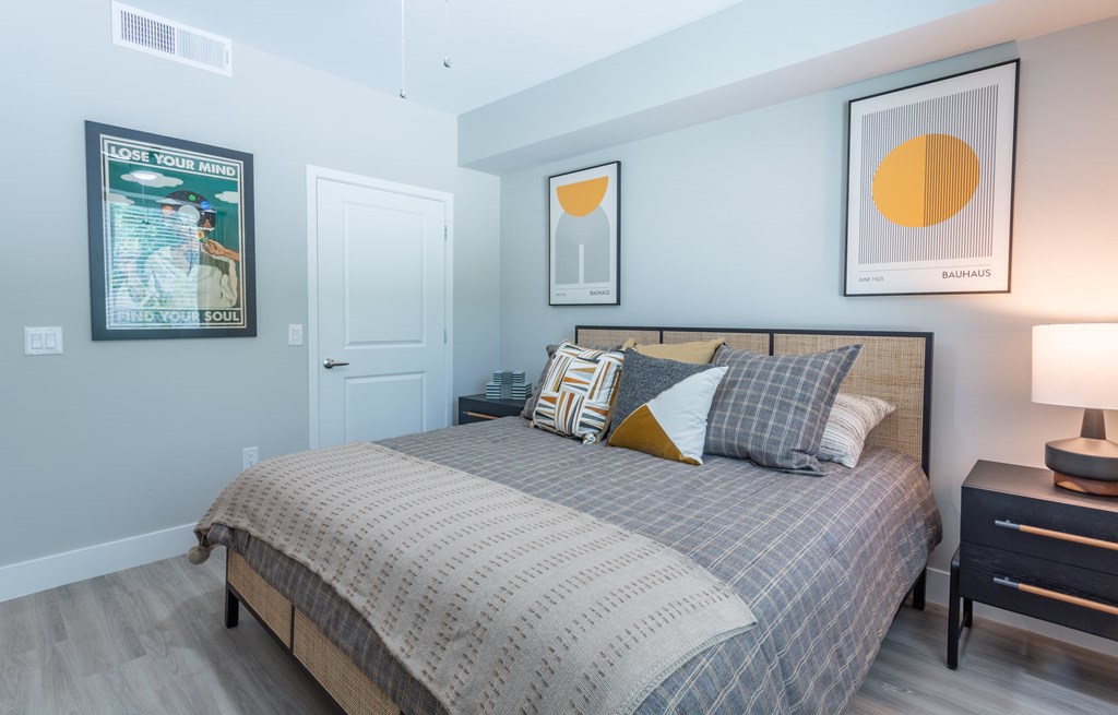 A bedroom with a bed, nightstand, and two framed pictures on the wall.