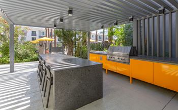 A modern outdoor kitchen area with a grill and a bench.