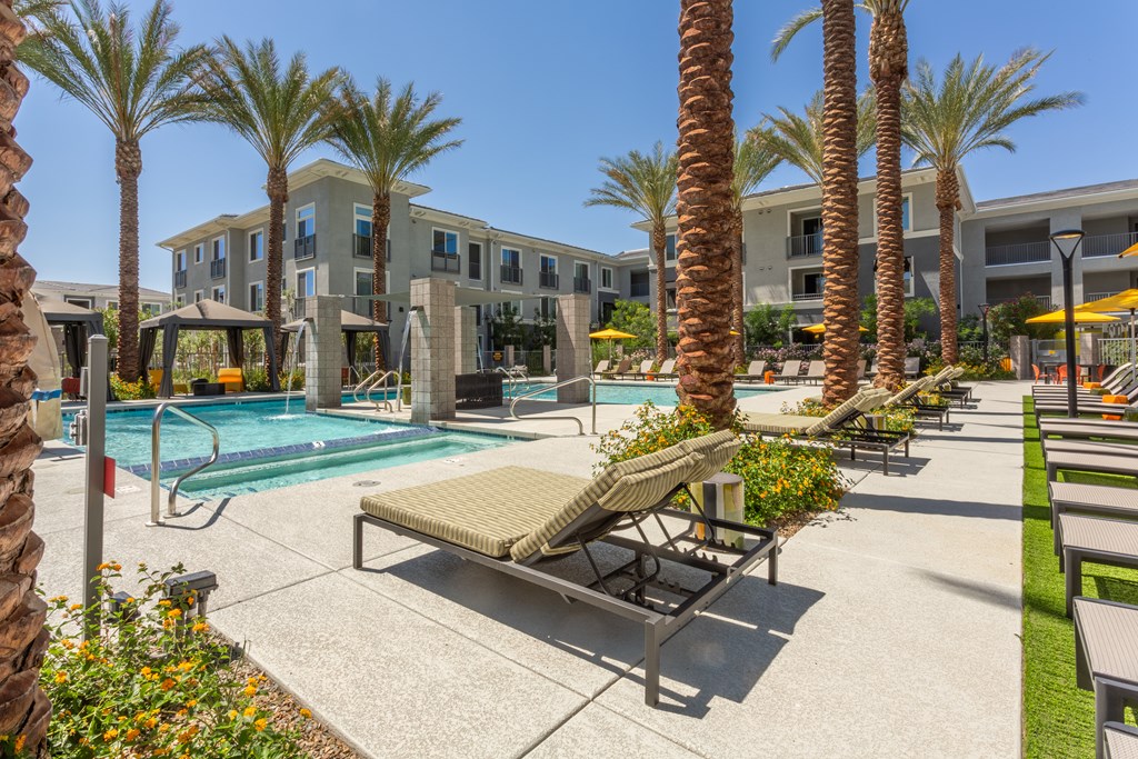 A pool surrounded by palm trees and a sun lounger.