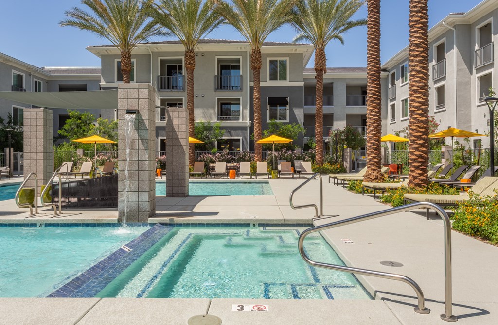 A swimming pool surrounded by palm trees and yellow umbrellas.
