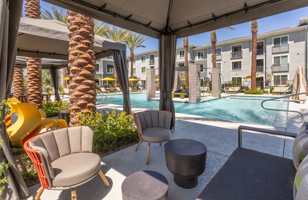 A patio with a table and chairs overlooking a pool.