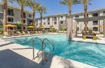 A swimming pool surrounded by palm trees and lounge chairs.