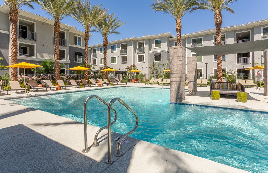 A swimming pool surrounded by palm trees and lounge chairs.