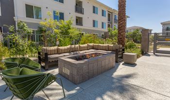 A patio with a fire pit and chairs.