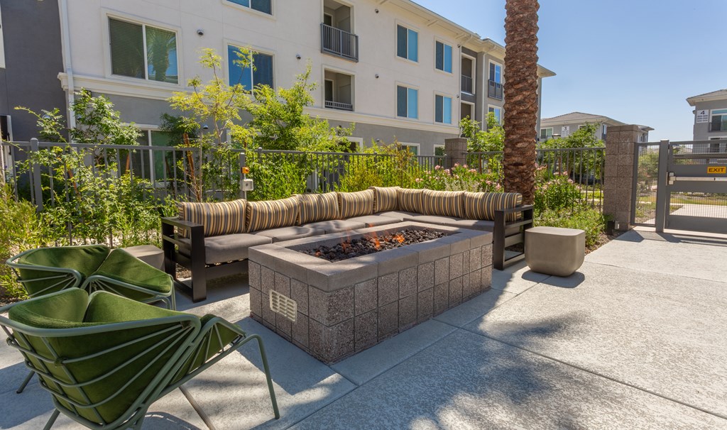 A patio with a fire pit and chairs.
