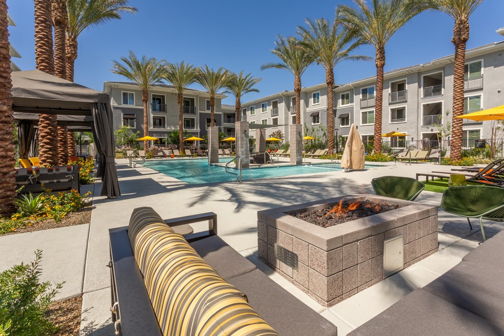 A pool area with a fire pit and lounge chairs.