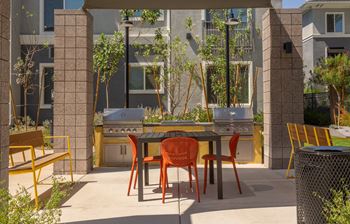 A patio with a table and chairs and a grill.