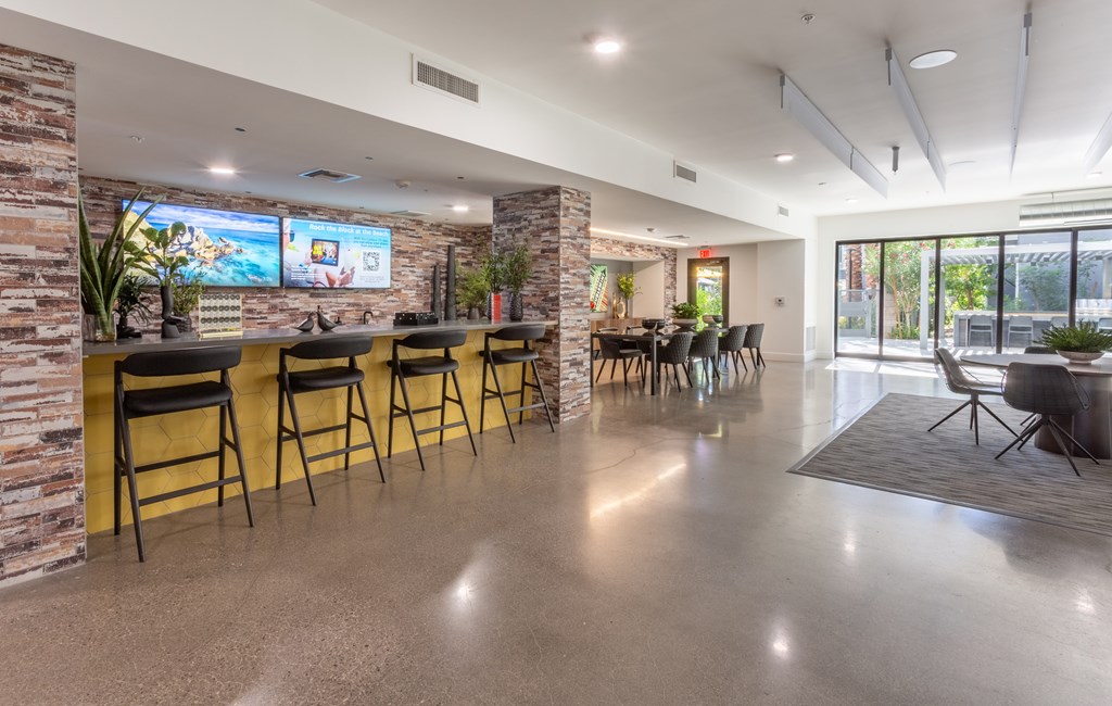 A modern bar area with a stone wall and a row of stools.