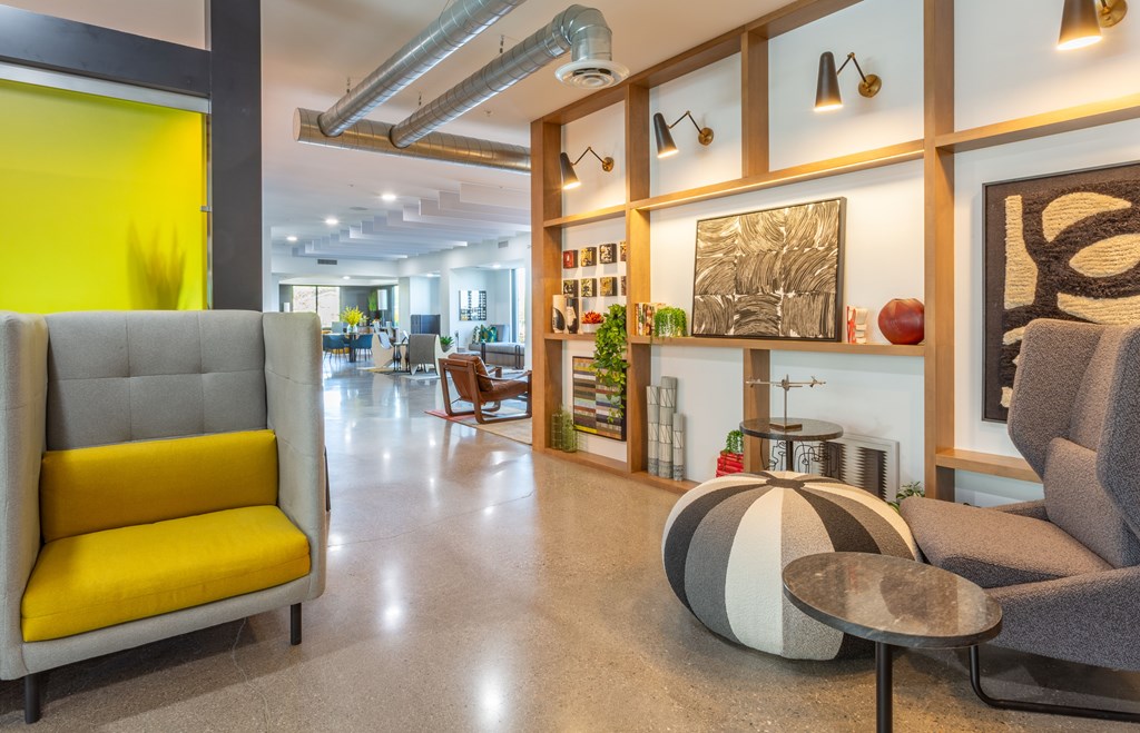 A yellow chair is in the foreground of a modern room.