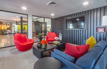 A living room with a blue couch, red chair, and a grey coffee table.