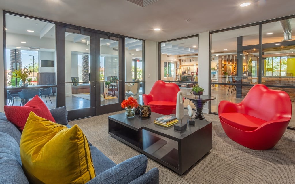 A modern living room with a grey sofa, red chairs and a coffee table.