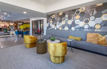 A modern living room with a grey couch and a grey and yellow patterned wallpaper.