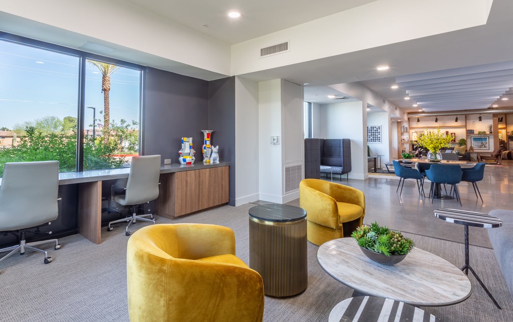 A modern office space with yellow chairs and a large window overlooking a palm tree.