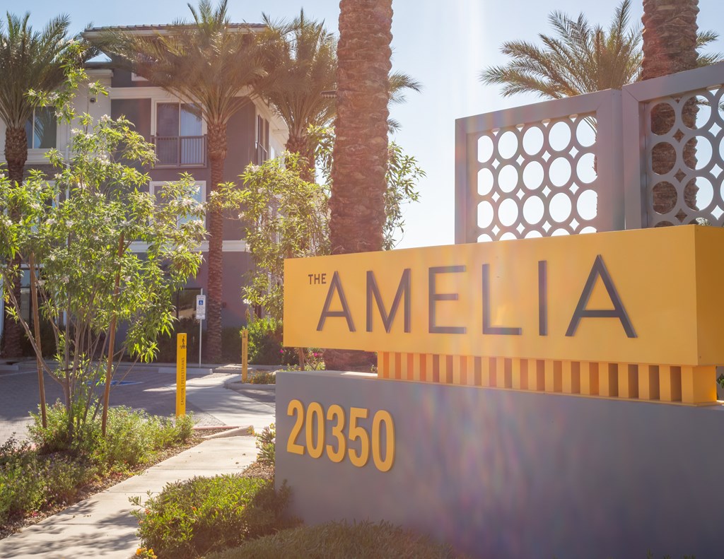 A sign for "The Amelia" is displayed in front of a building with palm trees.