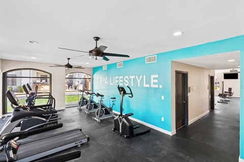 A gym with a row of treadmills and a wall that says "It's a lifestyle."