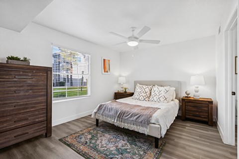 A bedroom with a bed, two lamps, and a ceiling fan.