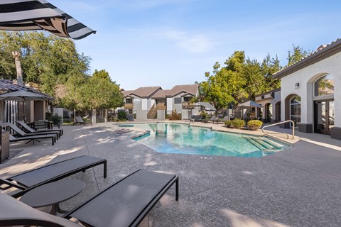 A pool surrounded by black lounge chairs and umbrellas.