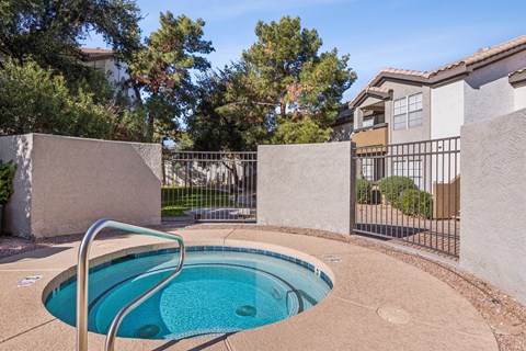A small residential pool surrounded by a concrete wall and a metal fence.