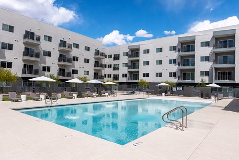Swimming pool with lounge chairs and umbrellas at Lucero Apartments, Phoenix, Arizona