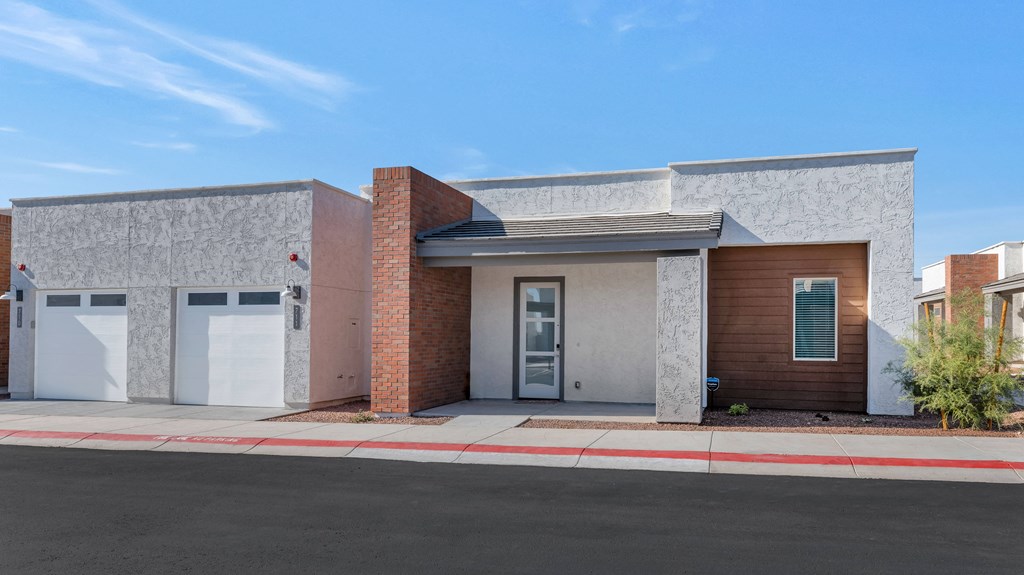 A modern house with a grey and brown facade and a red brick chimney.at Marketside Villas at Verrado, Buckeye, AZ