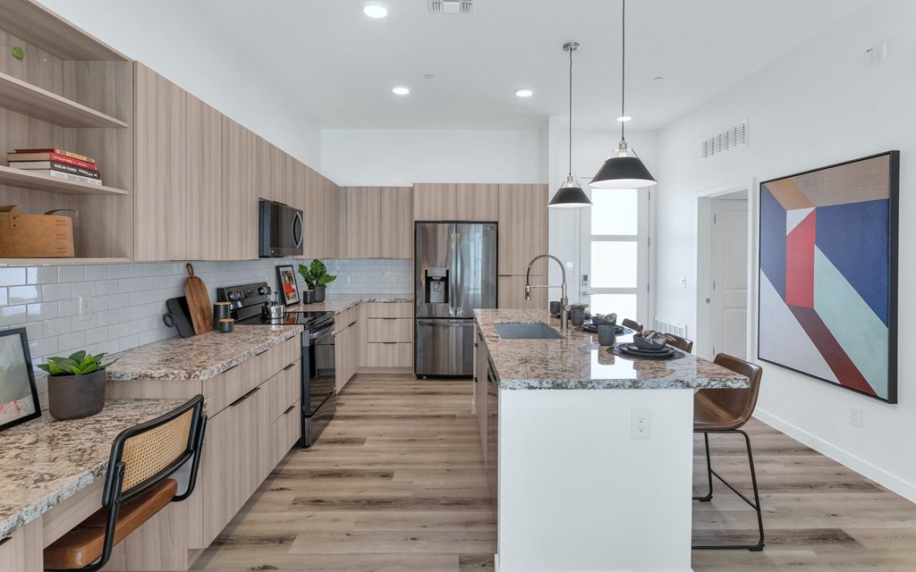 A modern kitchen with wooden floors and a marble countertop.at Marketside Villas at Verrado, Buckeye, 85396