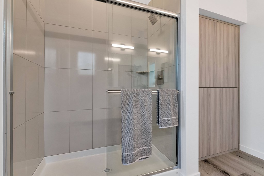A bathroom with a glass shower door and a towel hanging on the side.at Marketside Villas at Verrado, Buckeye, 85396