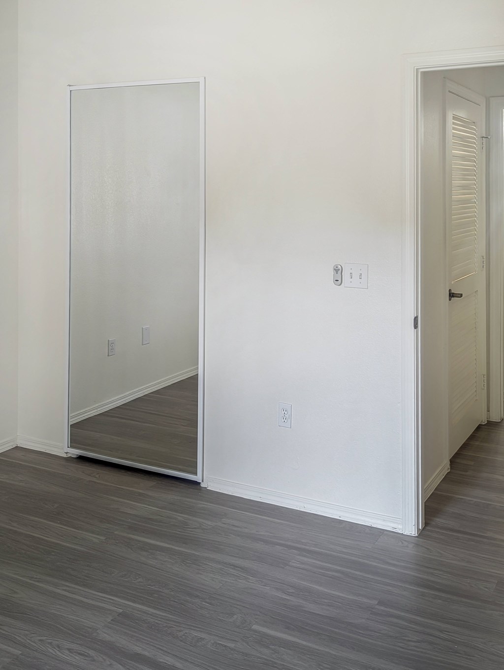 A room with a white door and a mirror on the wall.