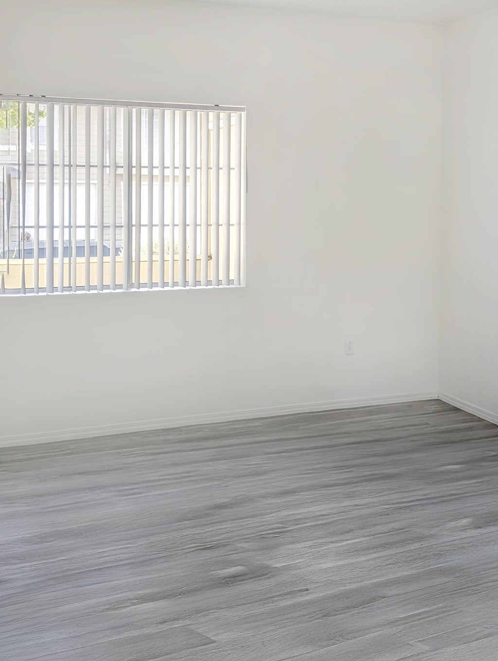 A room with a window and wooden flooring.