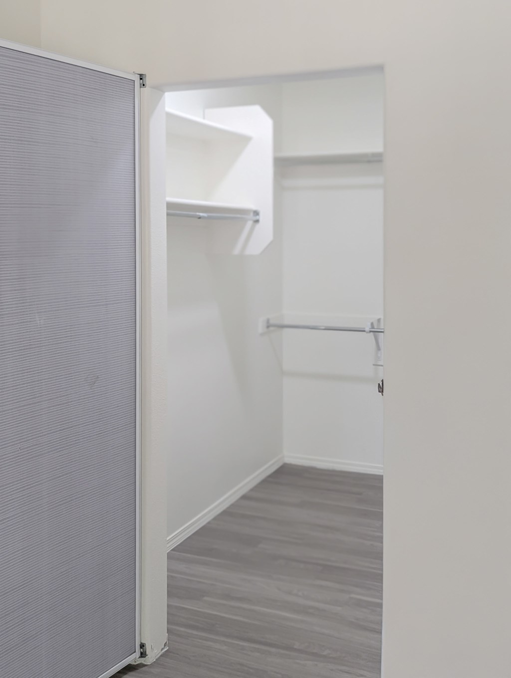 A white door is open to a hallway with a grey floor.