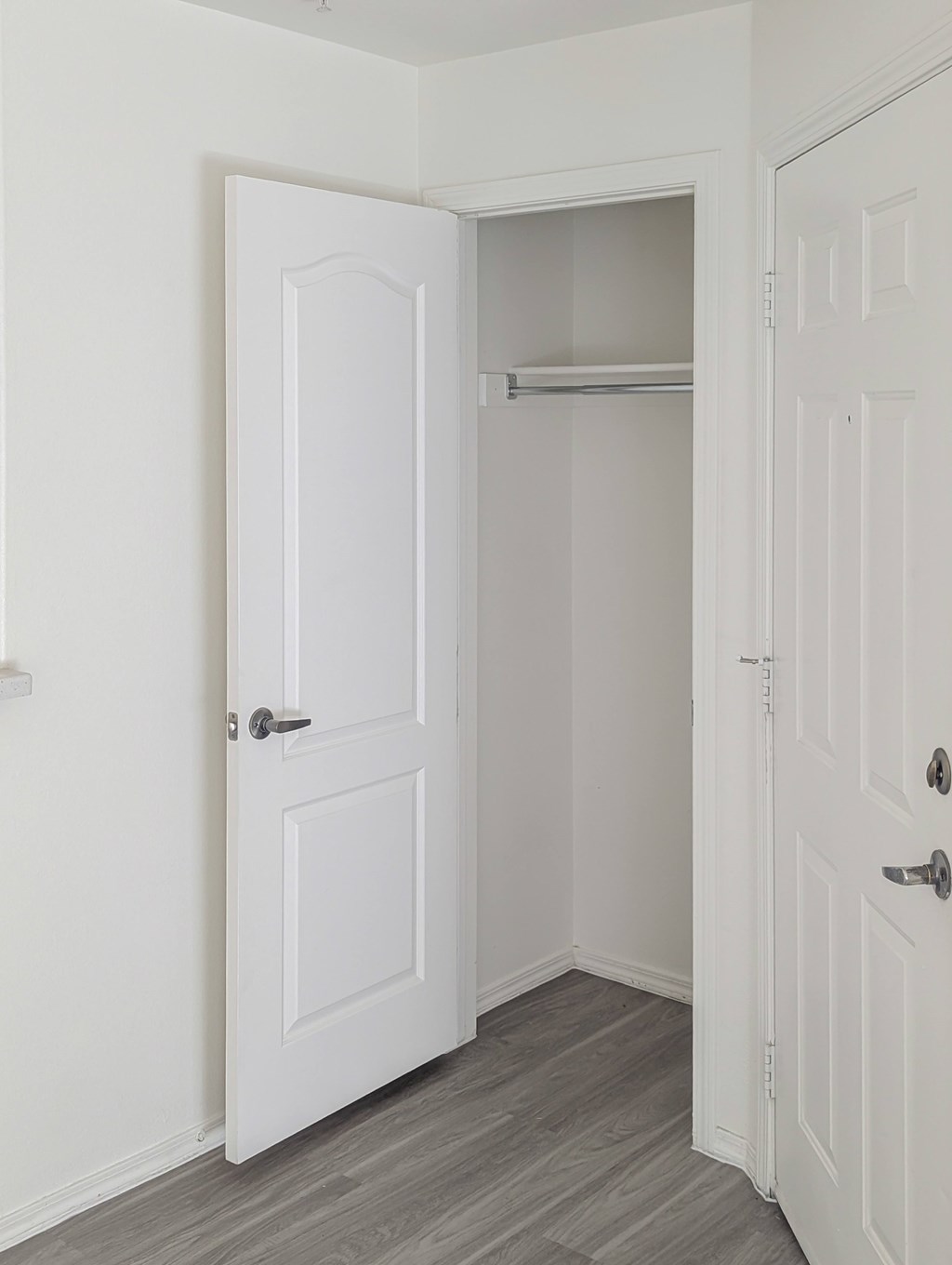 A white door is open to a closet with a shelf.