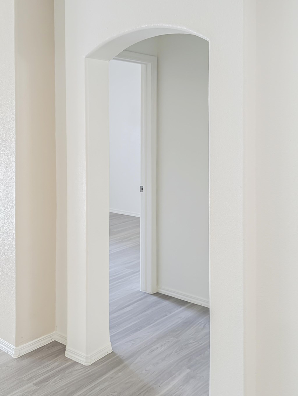A white doorway leads to a room with a grey floor.