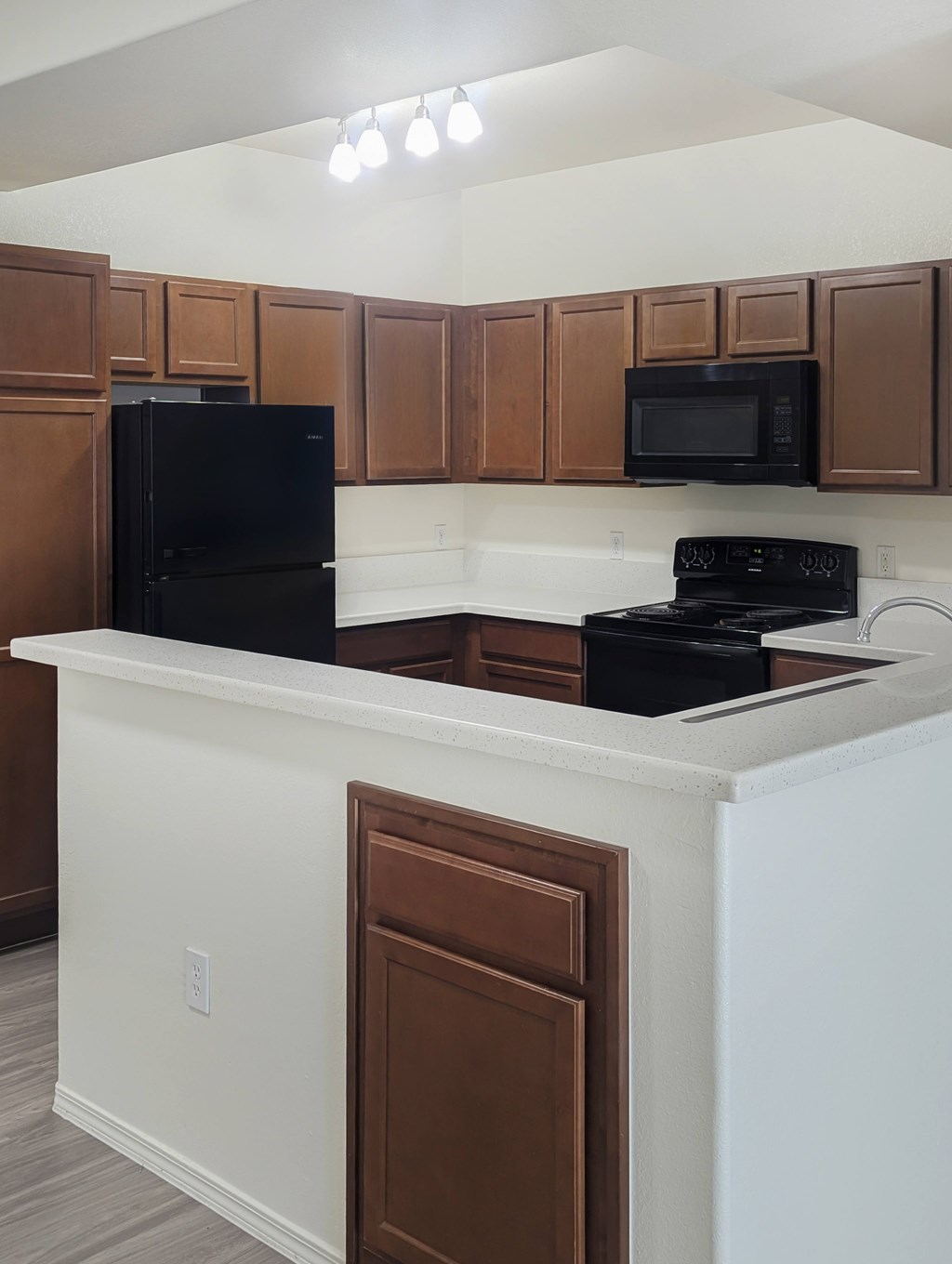A kitchen with black appliances and brown cabinets.