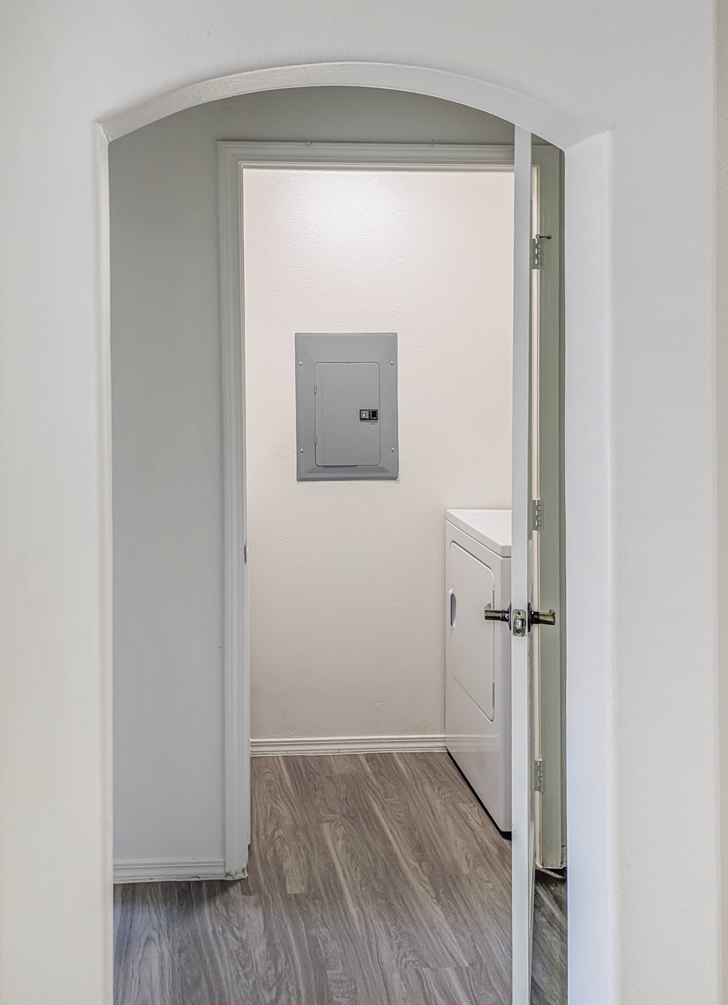 A white door with a grey frame is open to a hallway.