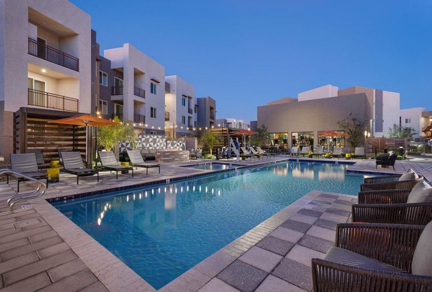a swimming pool with lounge chairs and umbrellas in front of a building a swimming pool with lounge chairs and umbrellas in front of a building at The Landing at Fiesta Village, Mesa, Arizona, 85210