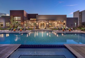 a swimming pool with lounge chairs and umbrellas in front of a building at The Landing at Fiesta Village, Arizona,  85210