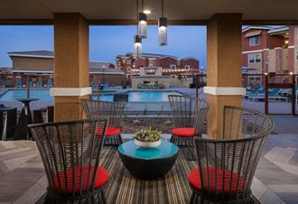 a patio with a table and chairs and a pool in the background at Zaterra Luxury Apartments, Chandler, AZ, 85286