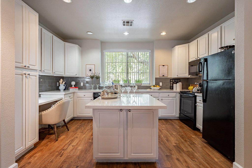 A kitchen with a black refrigerator and white cabinets.at Palazzo Townhomes, Arizona  