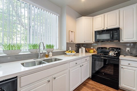 A kitchen with white cabinets and a black oven.