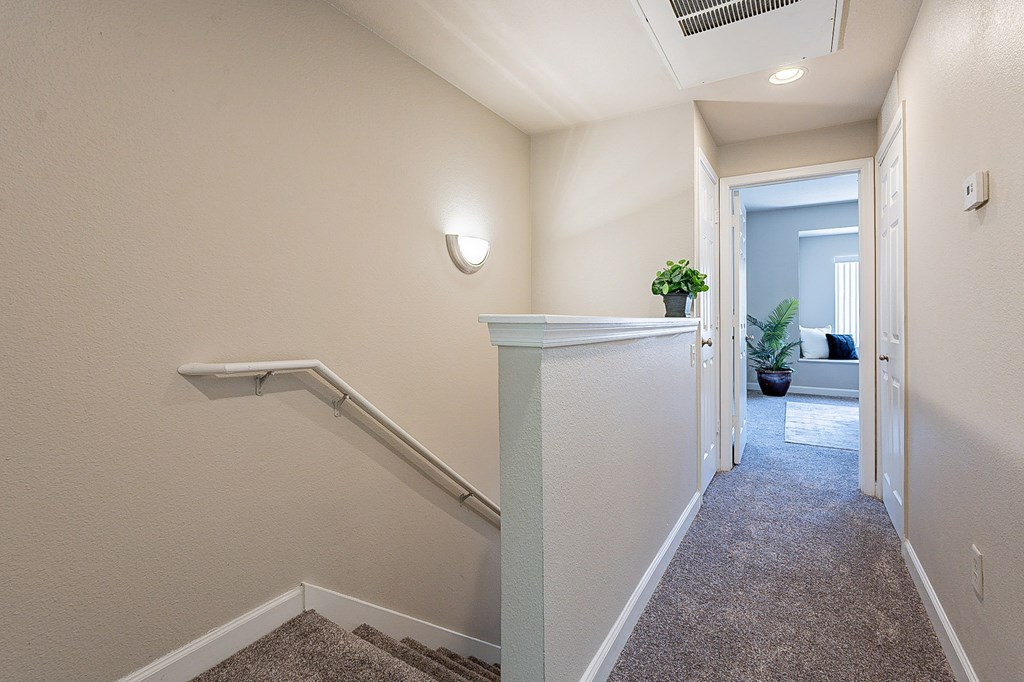 A hallway with a carpeted floor and a staircase on the left side.at Palazzo Townhomes, Phoenix, AZ 85008  