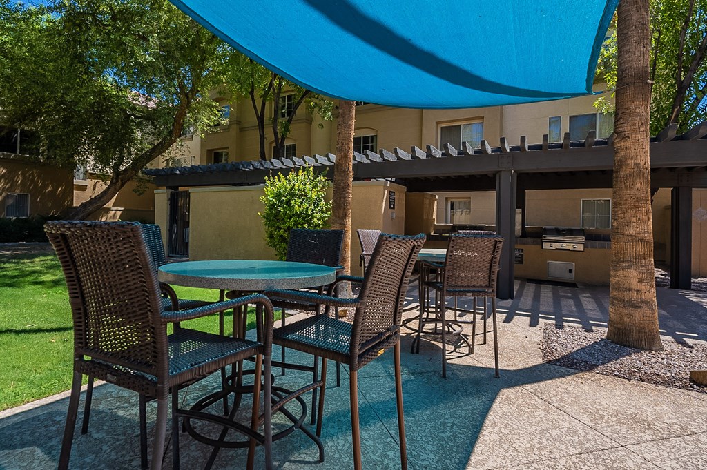A patio with a table and chairs under a blue umbrella.at Palazzo Townhomes, Phoenix, 85008  