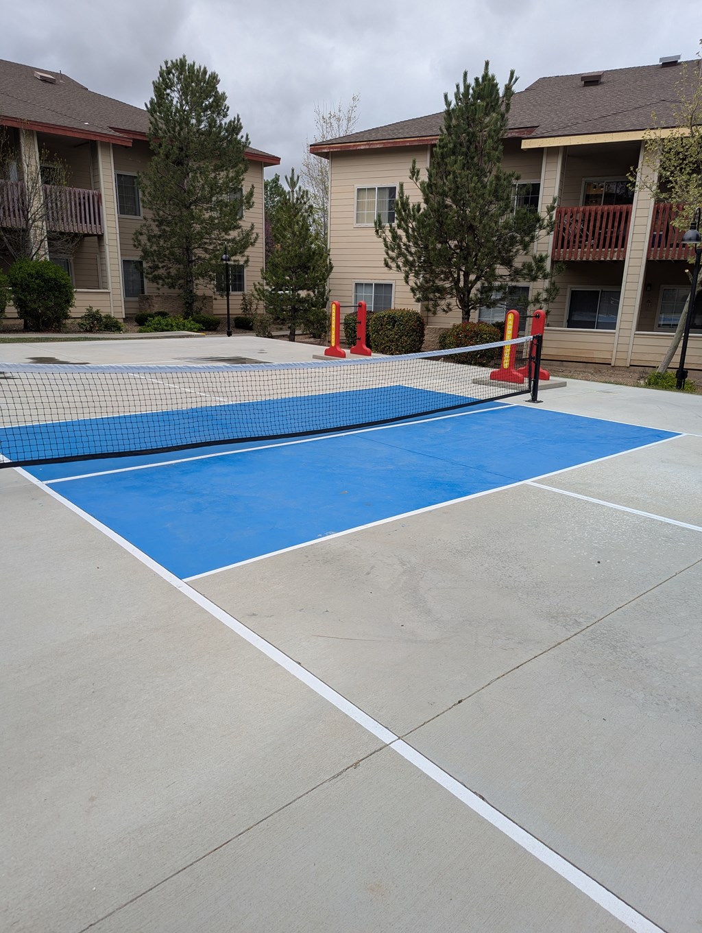 A blue and white tennis court with orange cones around it.