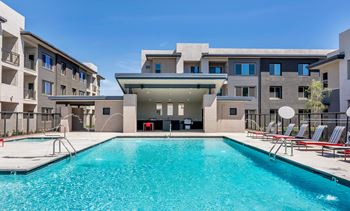 A swimming pool in front of a building with a red chair.