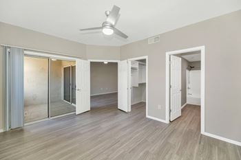 an empty living room with a ceiling fan and a mirrored closet