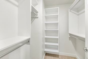 a walk in closet with white shelves and a white closet door