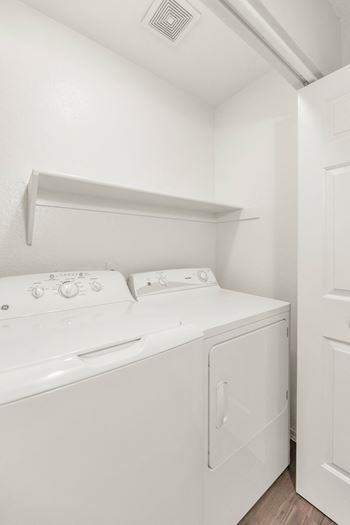 a white washer and dryer in a white room with a white door