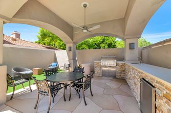 the outdoor patio has a grill and a table with chairs