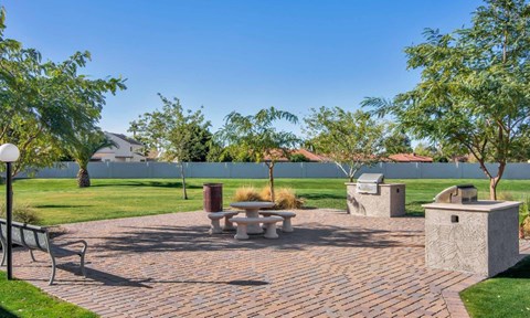 A park with a table and chairs surrounded by trees at Reflections at Red Mountain Apartments, Arizona