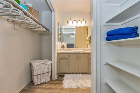 A bathroom with a white laundry basket and a white rug at Reflections at Red Mountain Apartments, Mesa, AZ