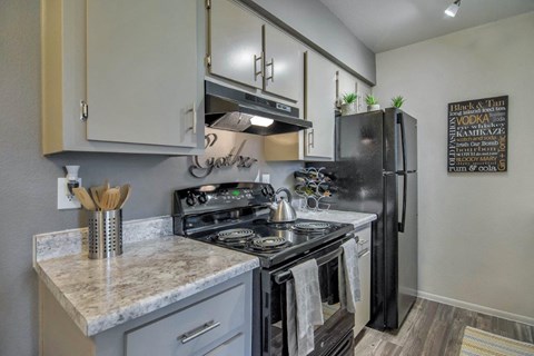 A kitchen with a black refrigerator and a white counter top at Reflections at Red Mountain Apartments, Mesa, Arizona